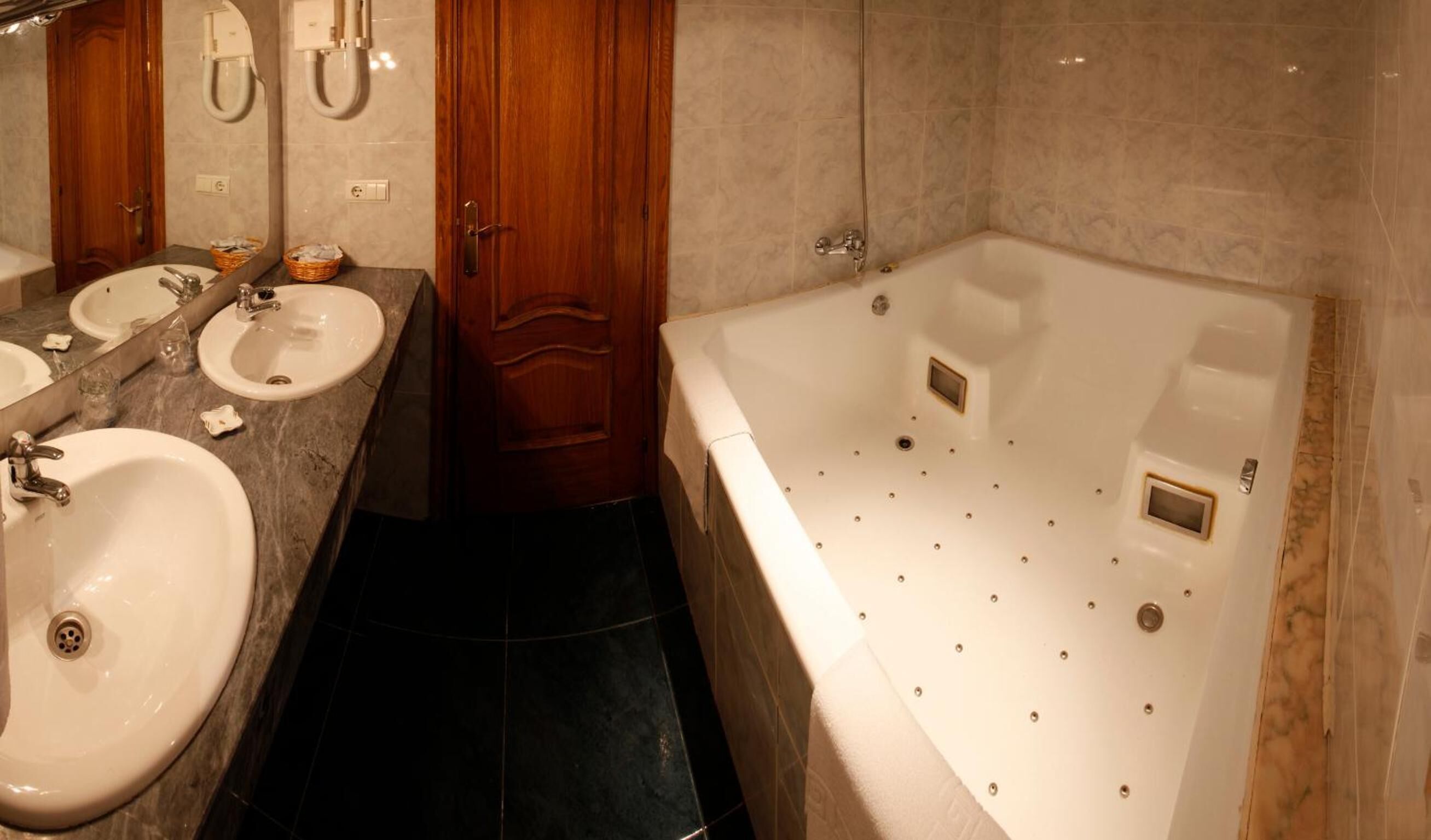 Un baño con dos lavamanos, una puerta de madera y una bañera grande.