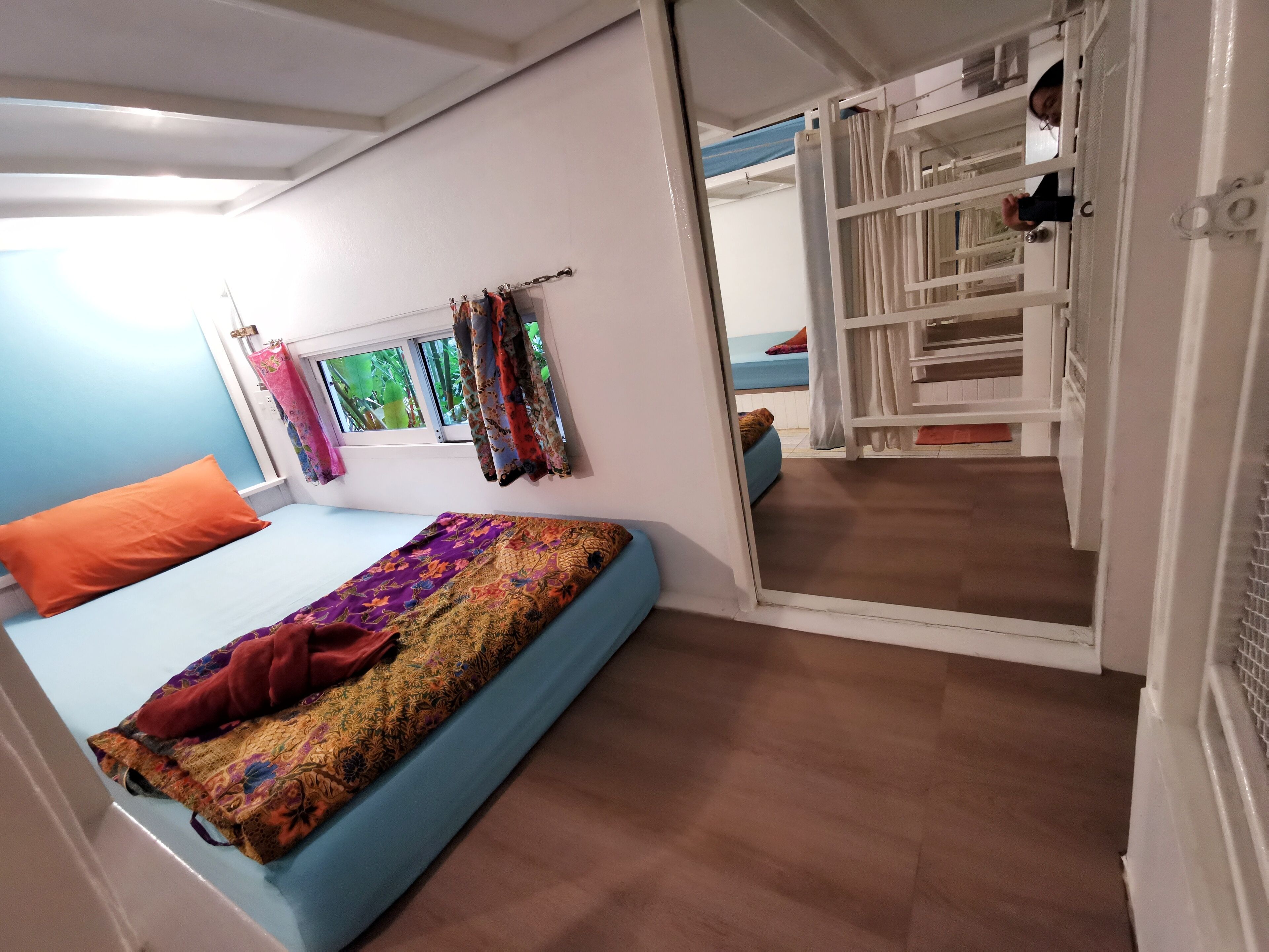 A bedroom with a bed, a window with curtains, and a view of the outside.