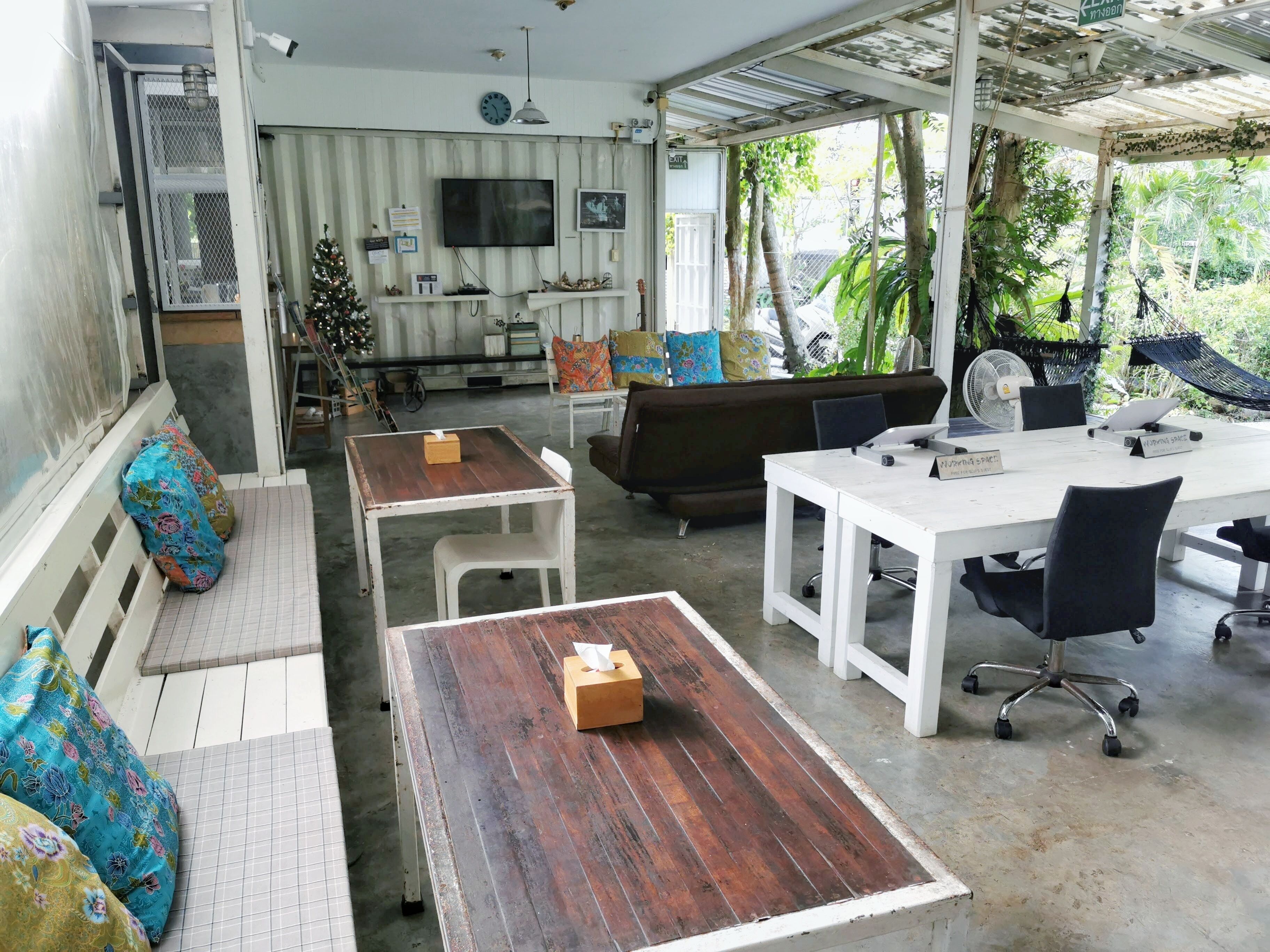 Un amplio salón de planta abierta con un televisor grande, asientos y vistas a zonas verdes.