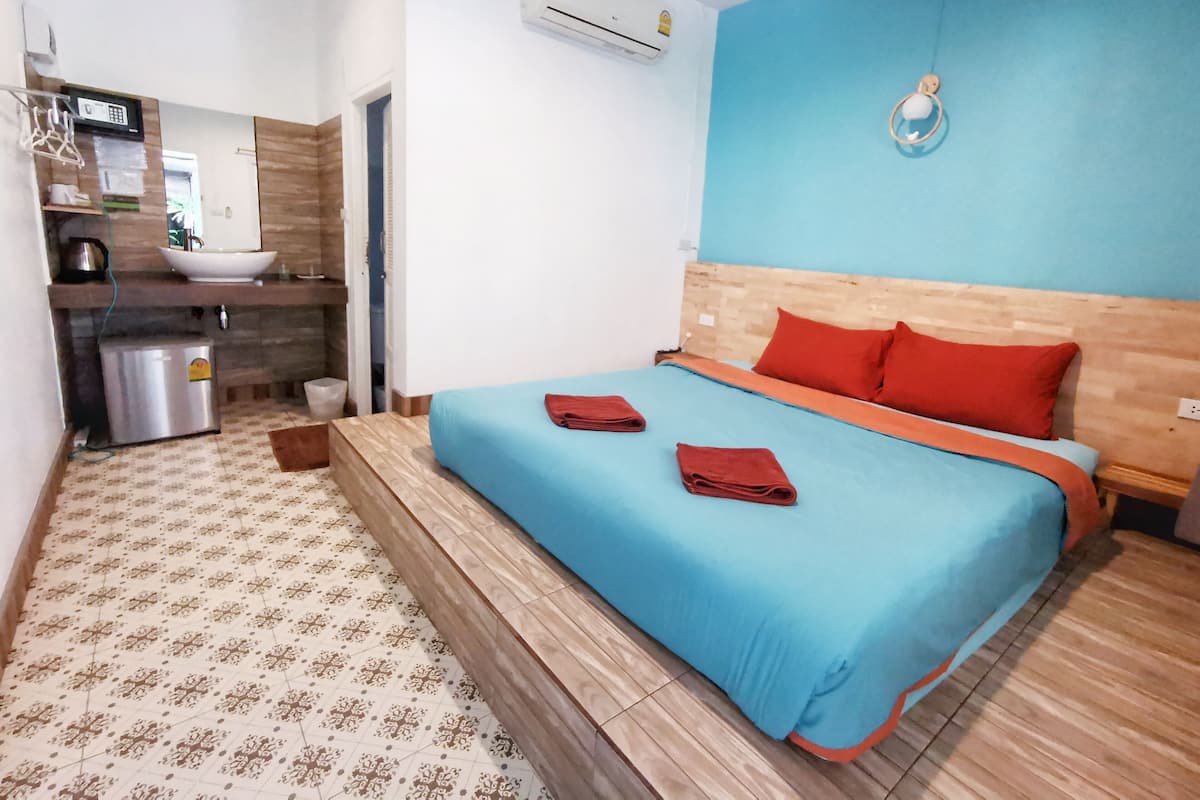 Una camera d'albergo con un letto, un angolo cottura, un lavandino e un condizionatore.