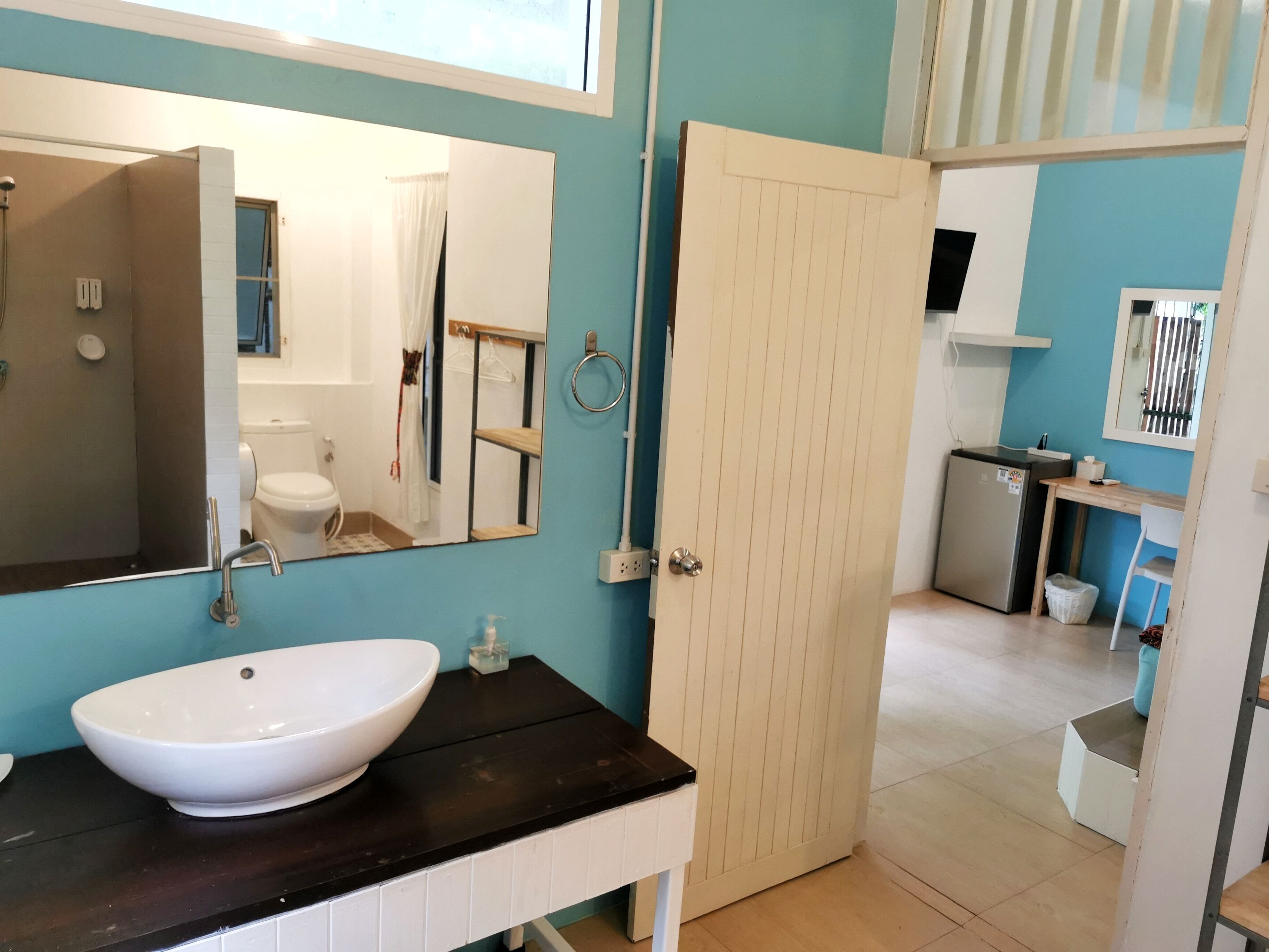 A bathroom with a white sink, a mirror, and a door leading to a bedroom.