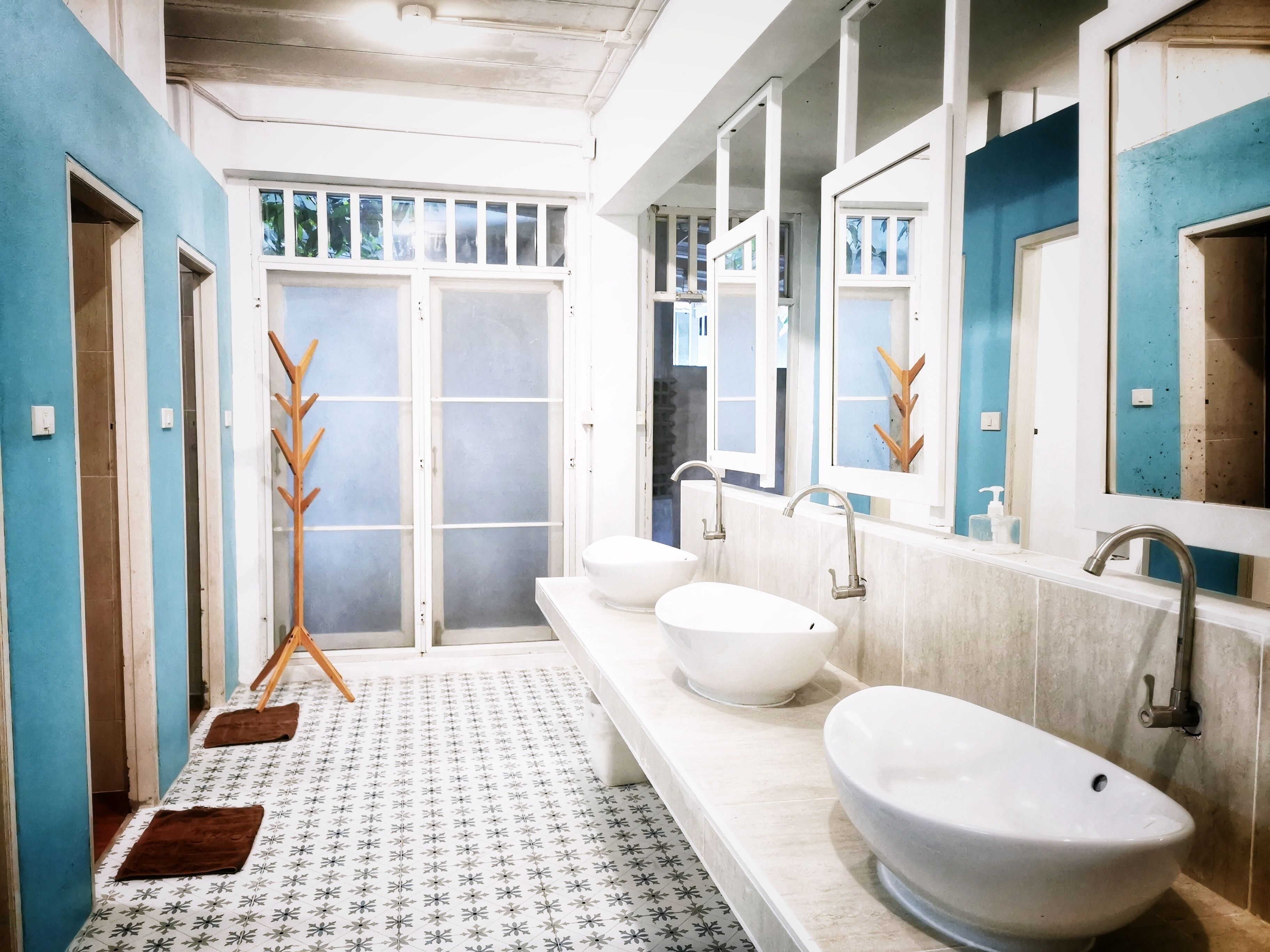 Un bagno con un lungo mobile lavabo, tre lavabi e uno specchio grande.