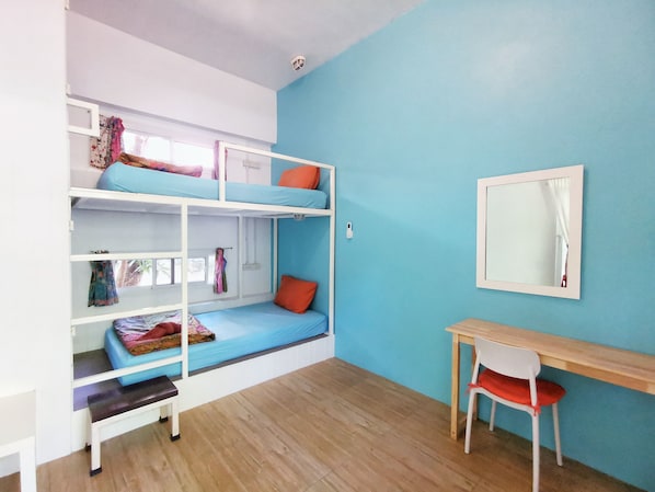 Habitación con literas, un escritorio y una silla, una ventana con cortinas y un espejo en la pared.