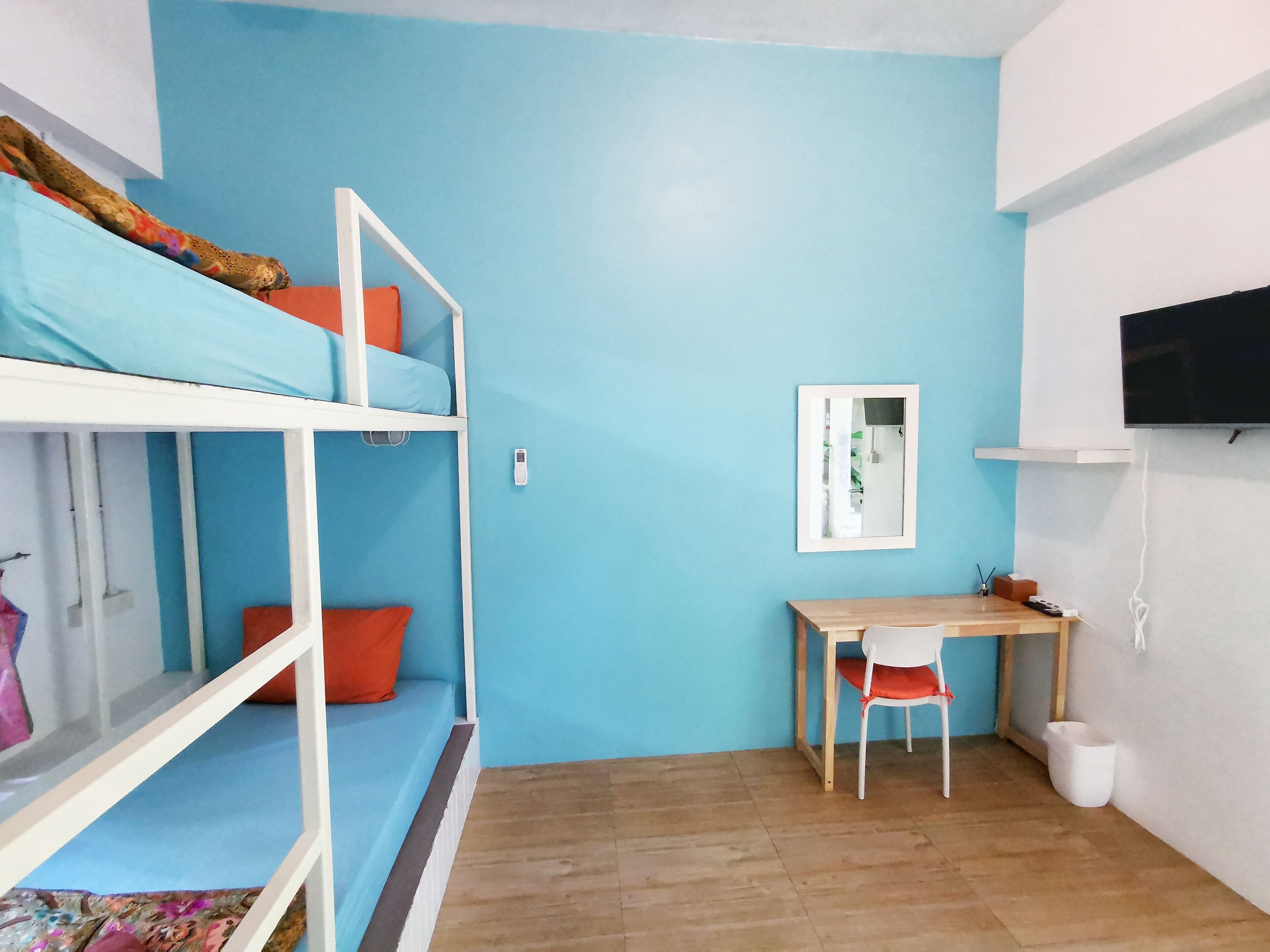 A small, brightly colored room with a bunk bed, a desk, and a chair.