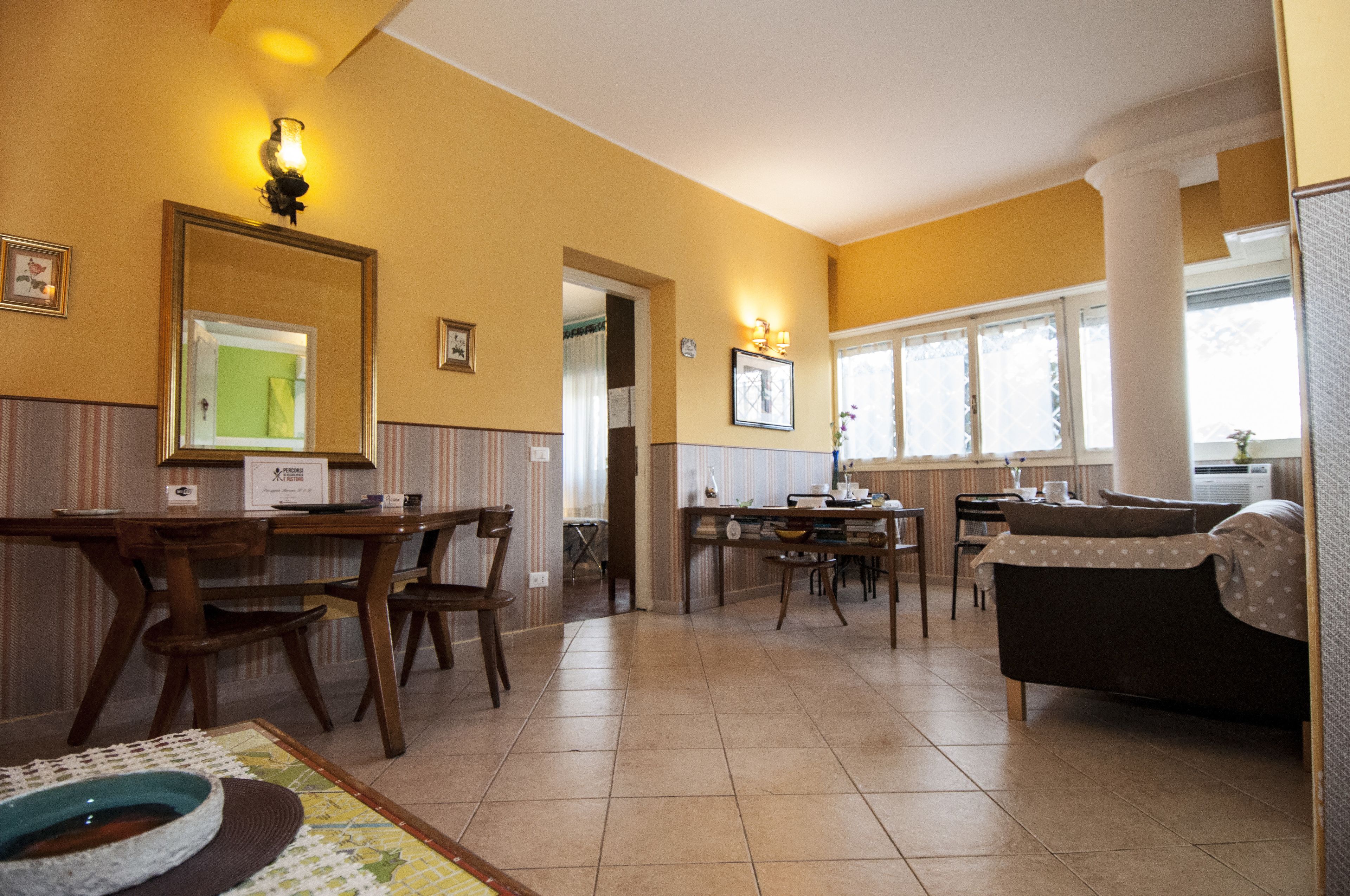 A spacious living area with a dining table, chairs, a sofa, and a kitchen area with a window.