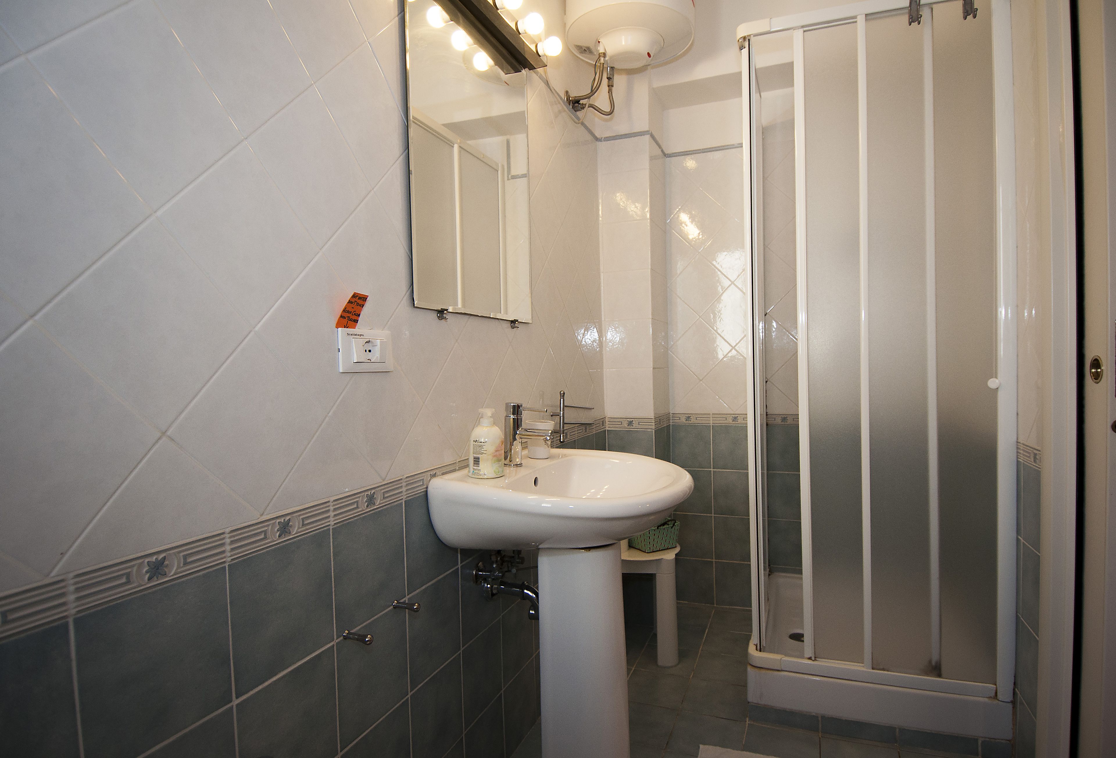 A bathroom with a white sink, mirror, and shower enclosure.