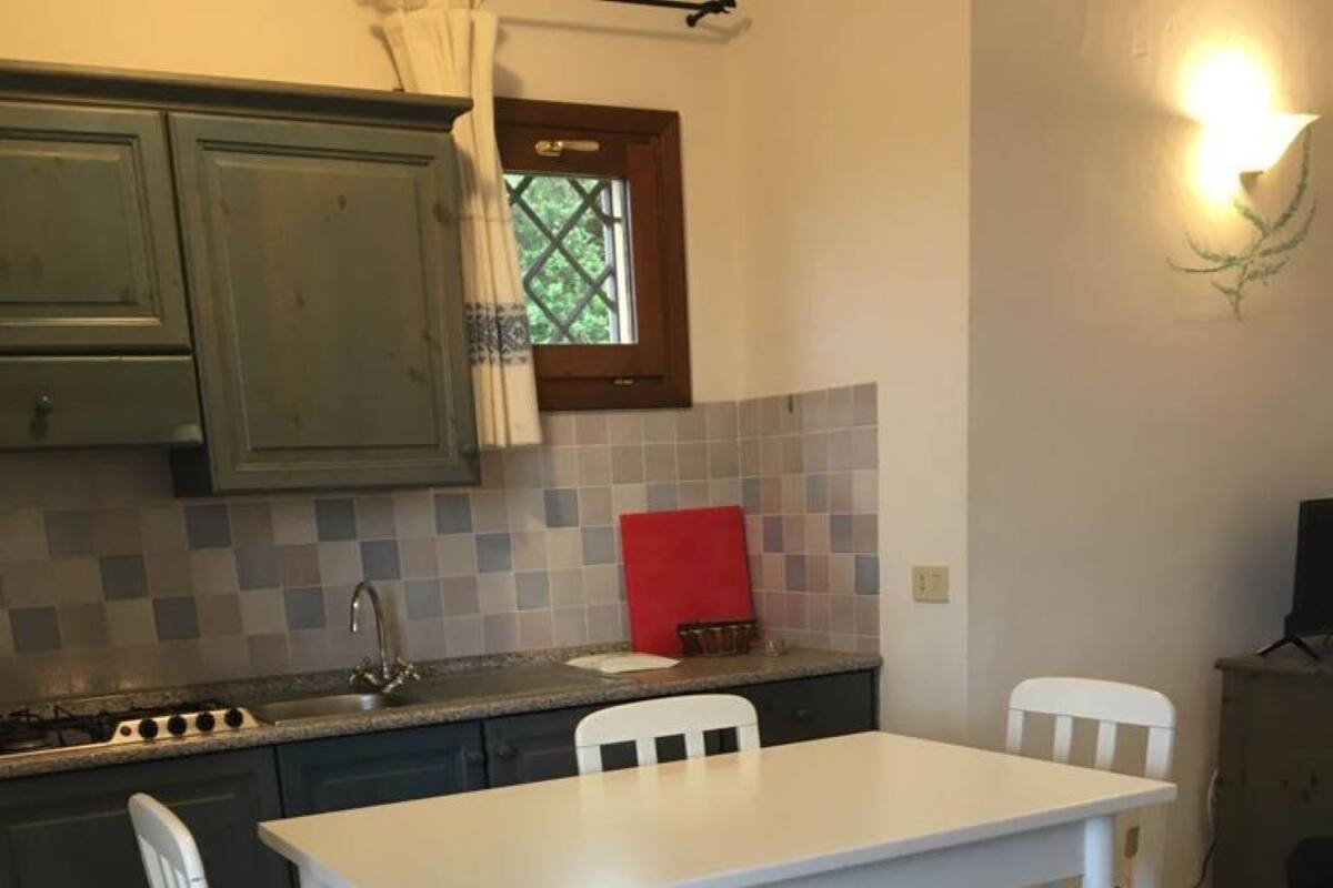 Une cuisine compacte comprenant une table et des chaises, une petite fenêtre et un luminaire fixé au mur.