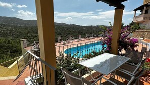 Una terrazza con piscina, area salotto all'aperto e vista sul paesaggio circostante.