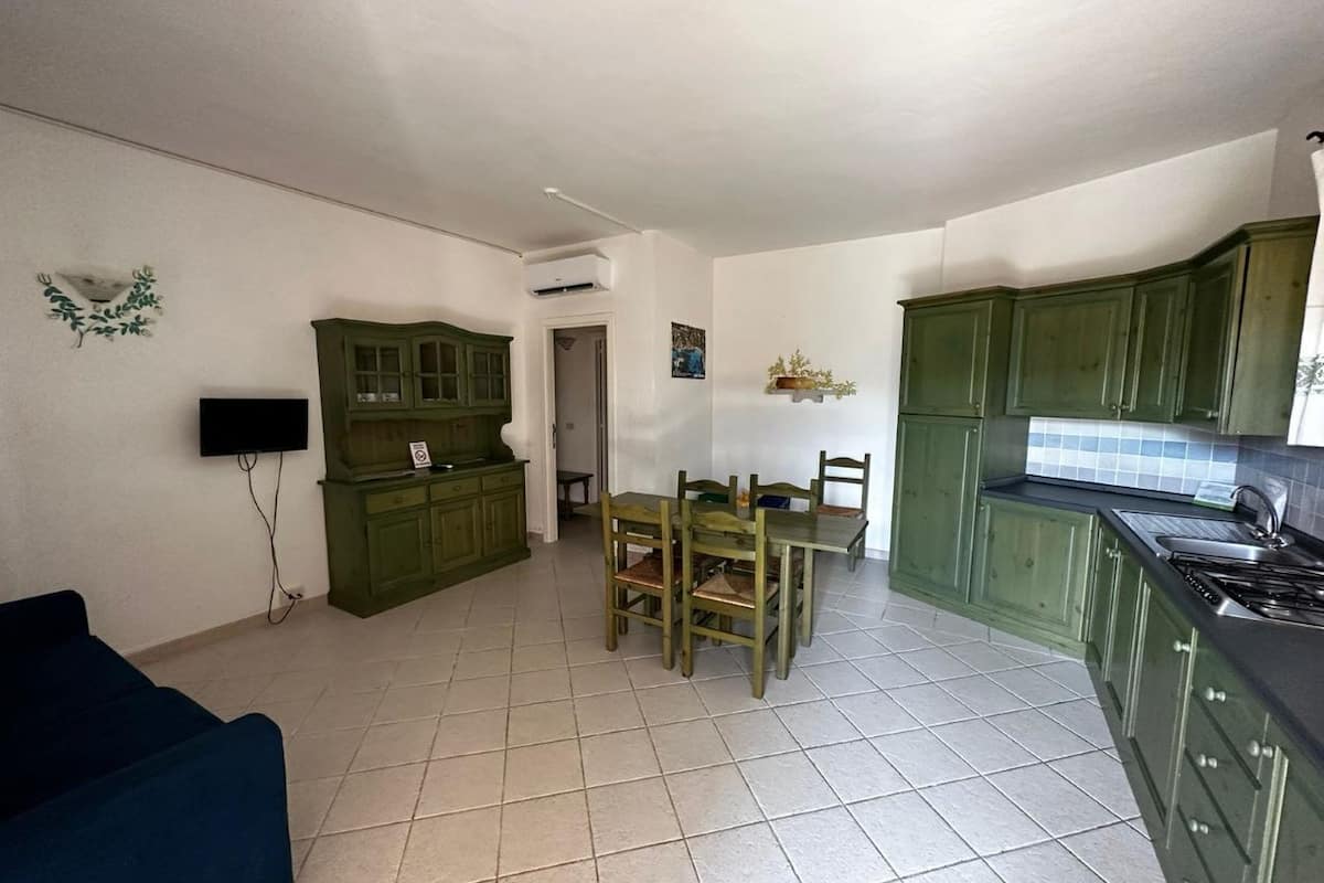 Un espace de vie compact comprenant un coin repas, une kitchenette et un téléviseur fixé au mur.