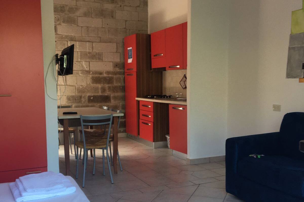 Un espace de vie compact comprenant un coin cuisine, un coin repas et un lit.