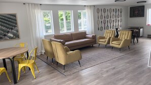 A modern living room with a brown sofa, yellow chairs, a wooden dining table, and tennis rackets on the wall. - Varsity North (Centralia)