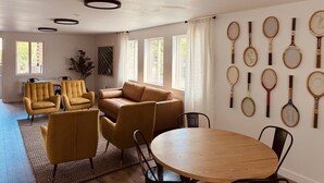 A modern living room with a sofa, chairs, a dining table, and tennis rackets on the wall. - Varsity North (Centralia)