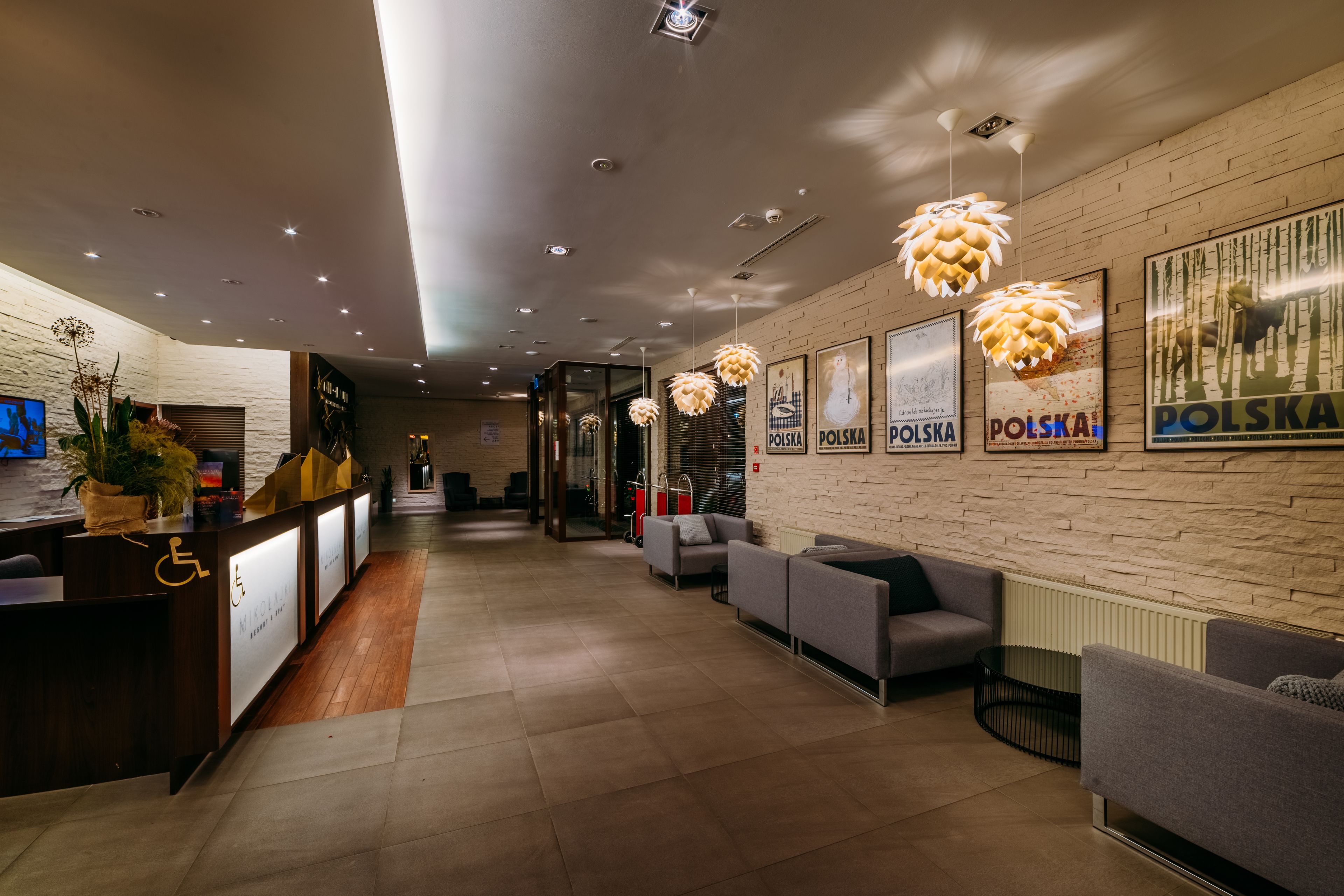 Una hall moderna di un hotel con reception, area salotto e opere d'arte alle pareti.
