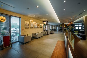 A spacious lobby with a wooden wall, multiple seating areas, and a reception desk. - Mikołajki Resort Hotel & Spa (Mikolajki)