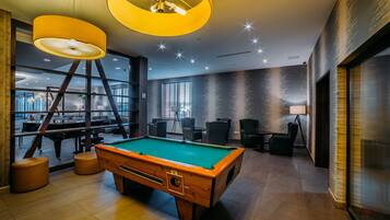 A billiards room with a pool table, chairs, and a large window.