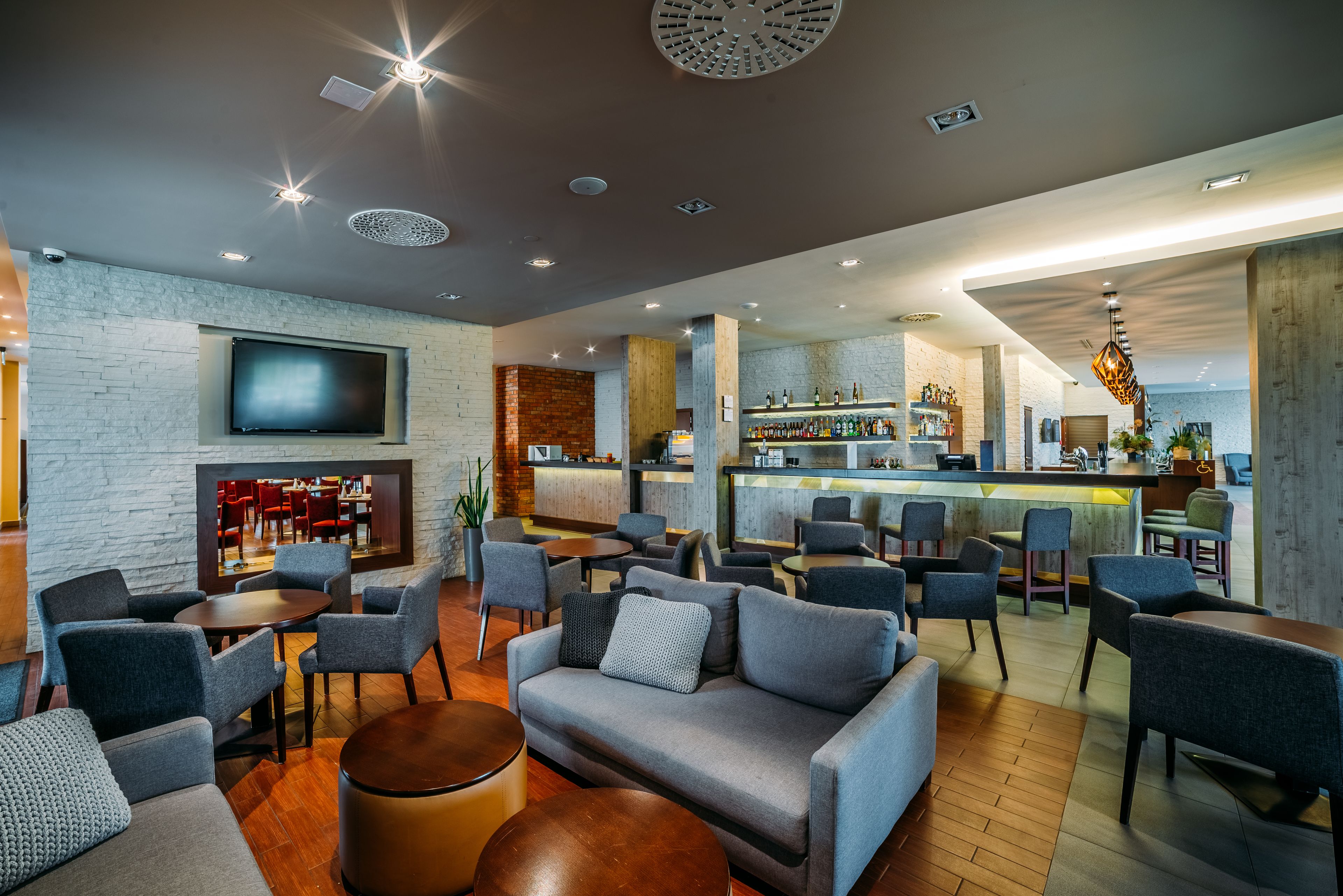 Ein stilvoller Lounge-Bereich mit Sofas, Sesseln, einer Bar und einem Fernsehbildschirm.