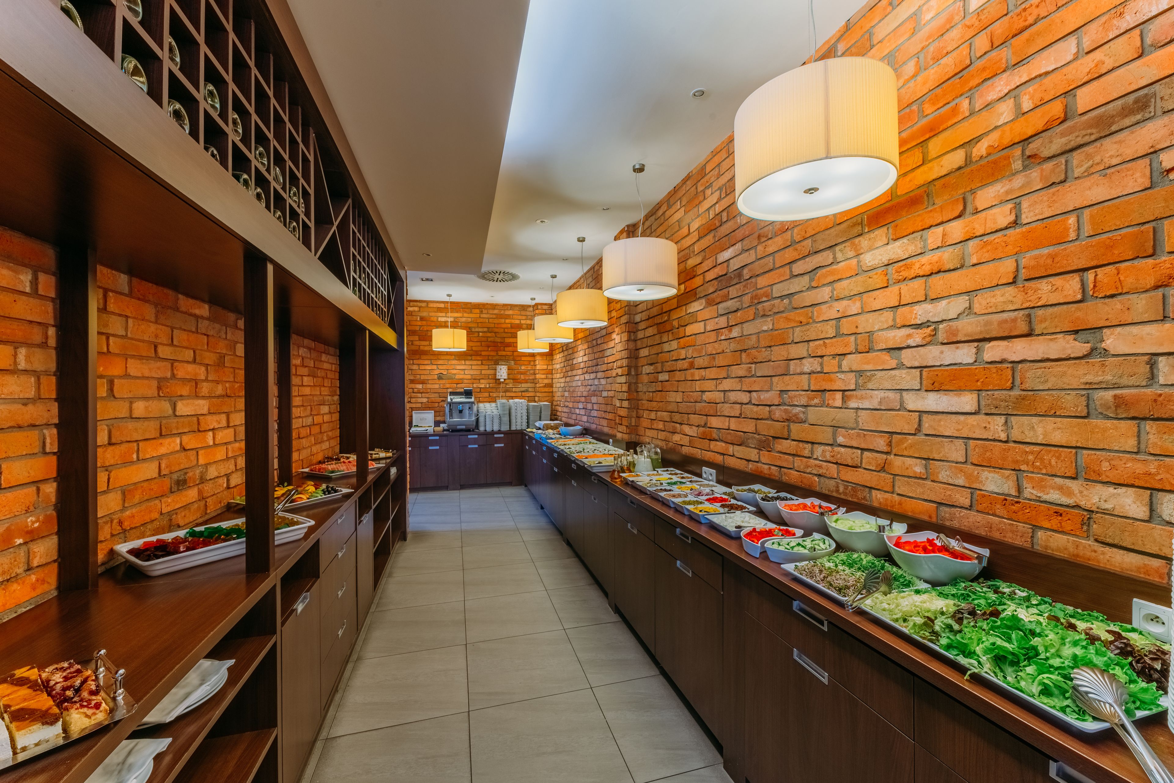 Un long buffet proposant une variété de plats, avec un mur en briques en arrière-plan.