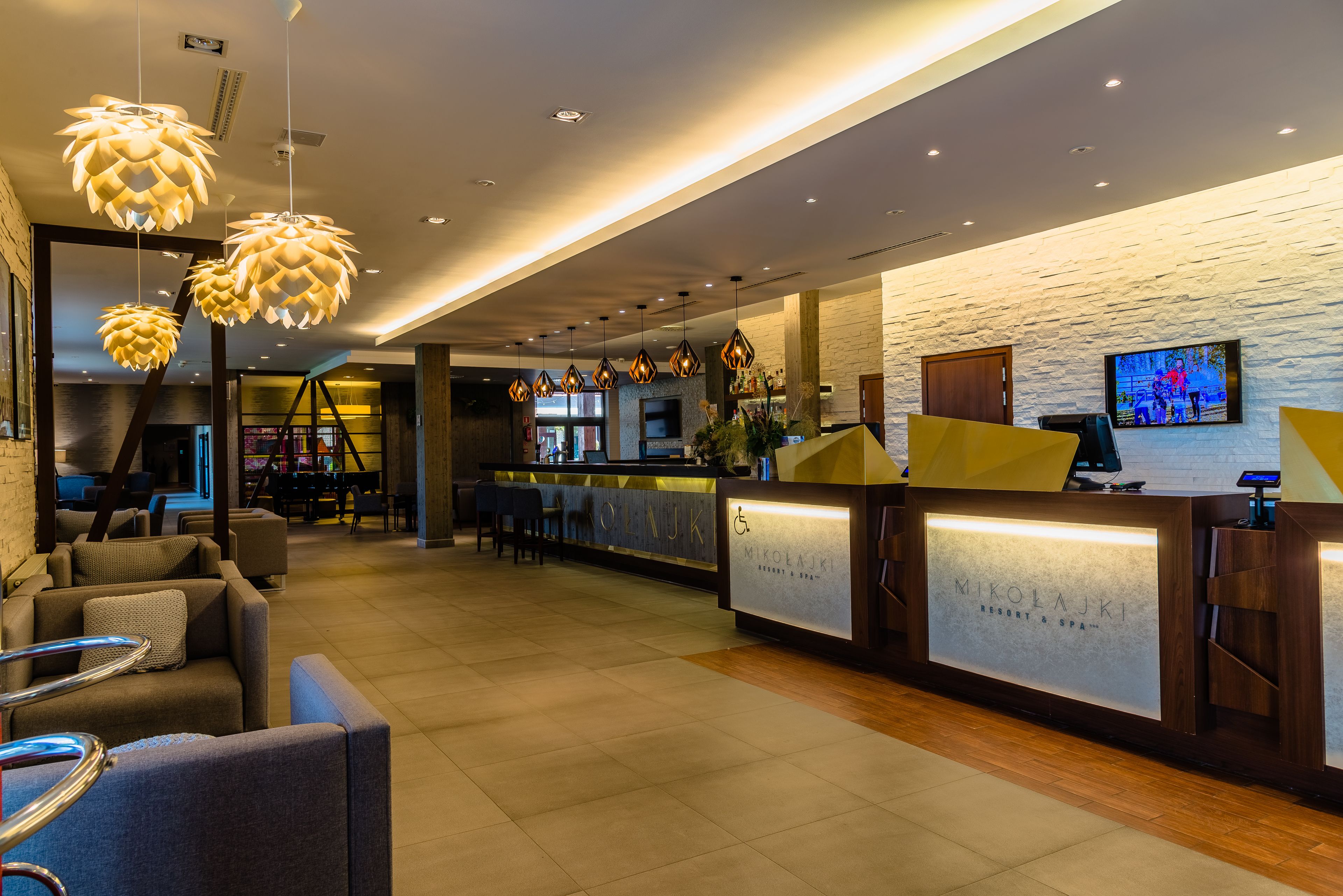A reception area with a modern design, featuring a reception desk, seating area, and a television screen.