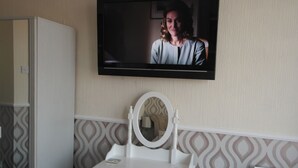Une salle de bain avec un meuble-lavabo, un téléviseur fixé au mur et un miroir.