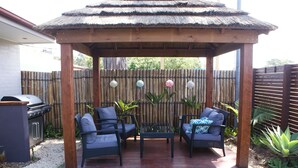 A covered patio with two wicker chairs and a table, surrounded by bamboo fencing and decorative lanterns. - Karuah Riverside Motel (Karuah)