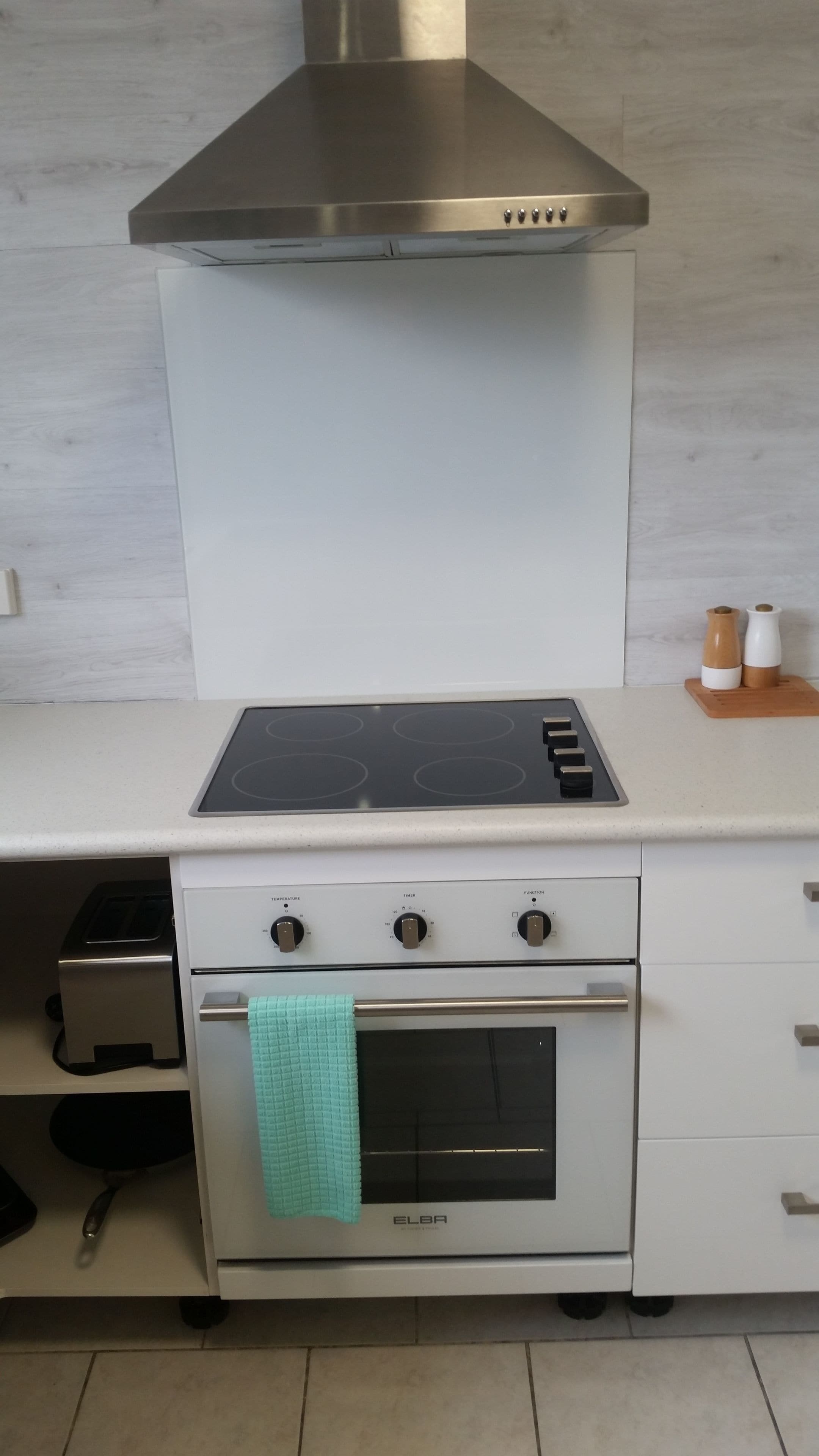 A kitchen with a stainless steel range hood, a built-in oven, and a stovetop.