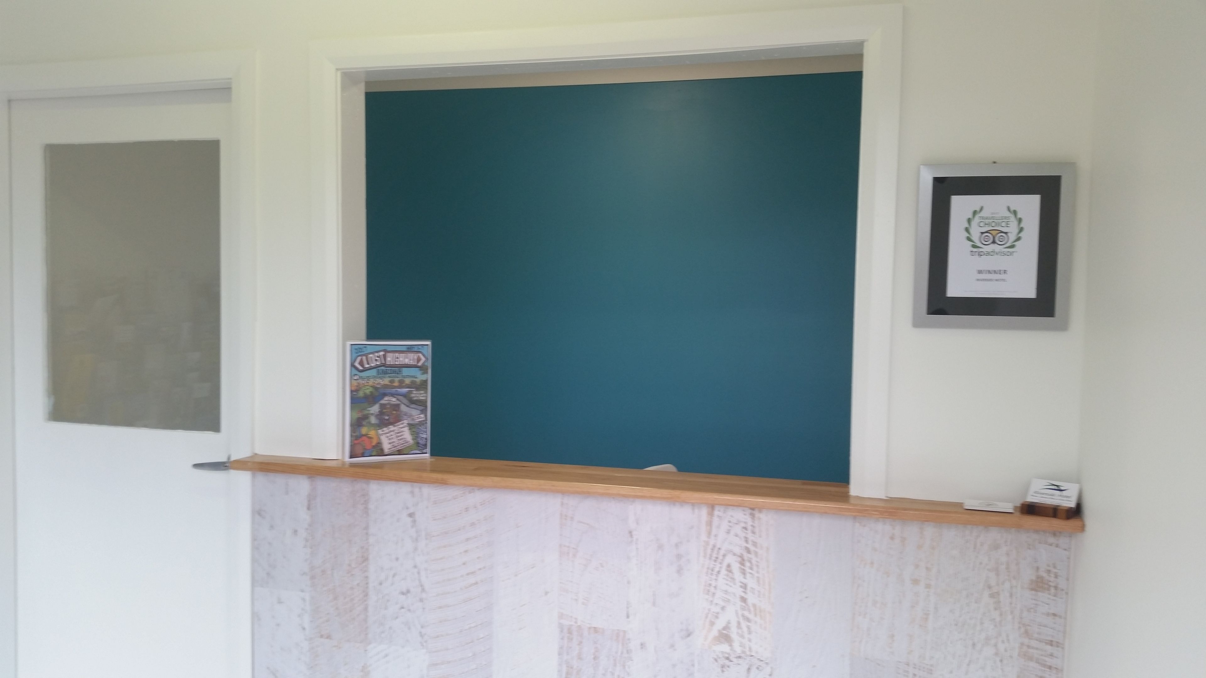 A reception area with a teal wall, a wooden counter, and a framed award on the wall.