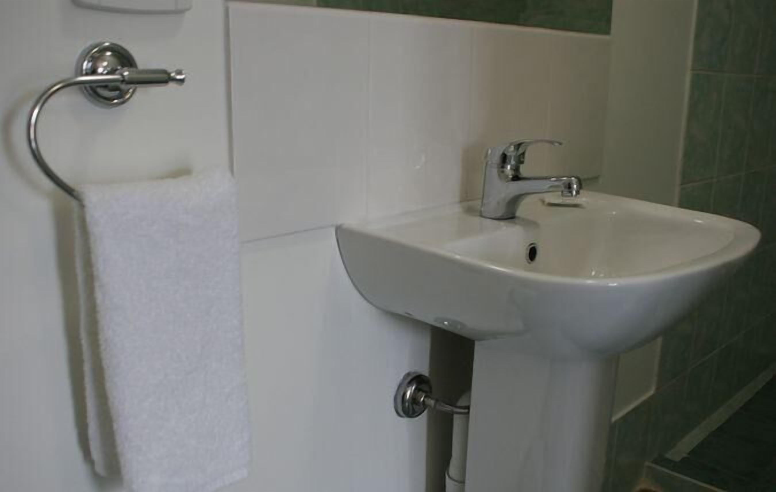 A bathroom with a white sink, a towel rack, and a toilet paper holder.