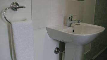 A bathroom with a white sink, a towel rack, and a toilet paper holder.