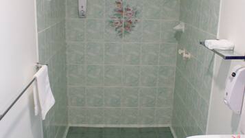 A bathroom with green tiles, a shower, a sink, and a towel rack.