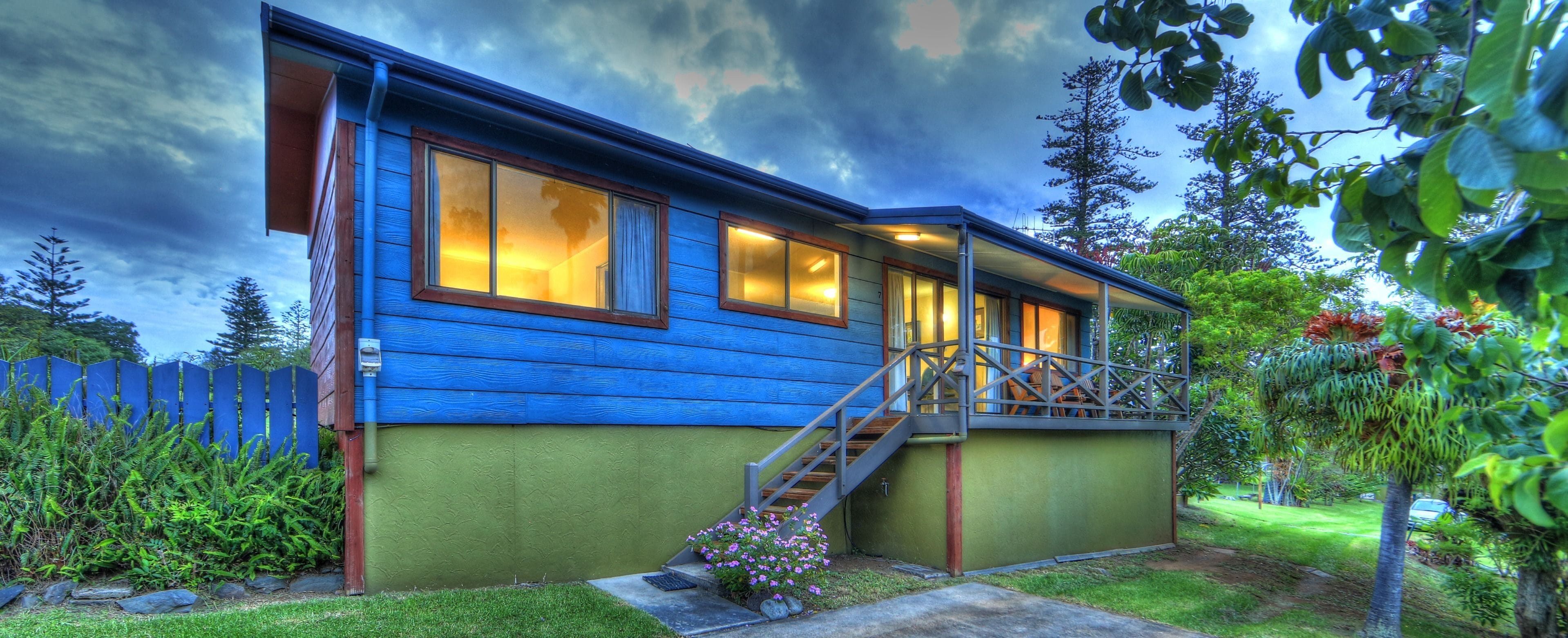 A two-story house with a blue exterior, a wooden staircase, and a green front door.