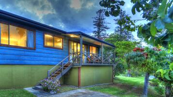 A two-story house with a blue exterior, a wooden staircase, and a green front door.