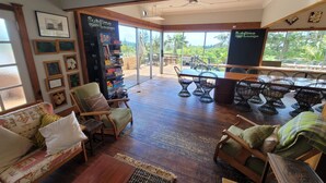 Ein großzügiger Lounge-Bereich mit Holzboden, bequemen Sitzgelegenheiten und großen Fenstern mit Blick ins Freie.