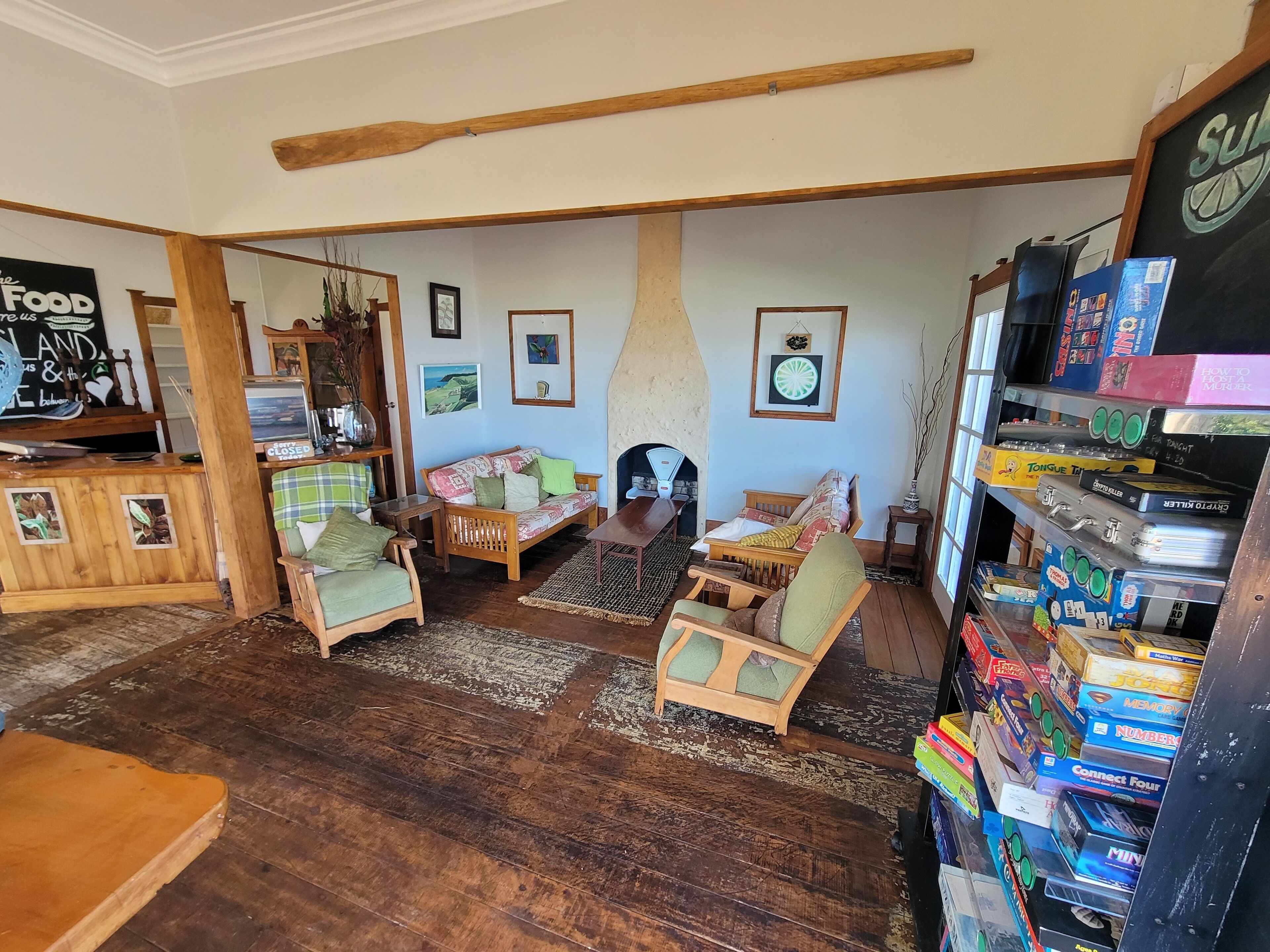 Een gezellige woonkamer met houten meubels, een open haard en een boekenplank vol gezelschapsspellen.