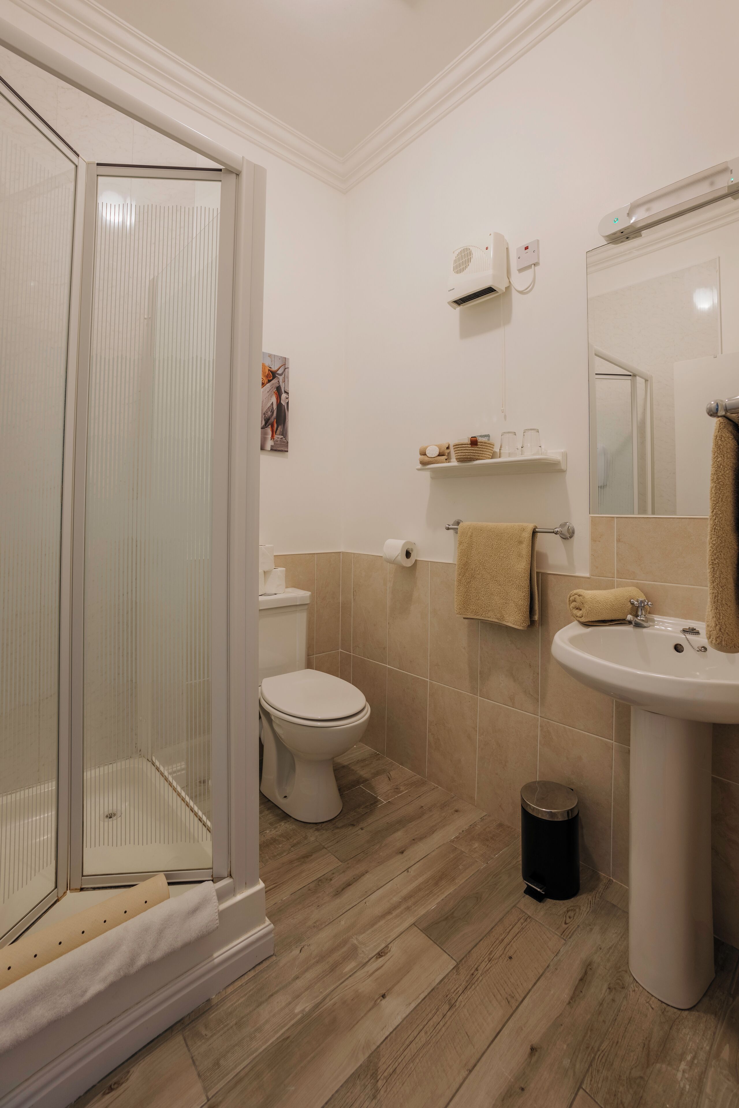 A bathroom with a shower, toilet, sink, and a mirror.