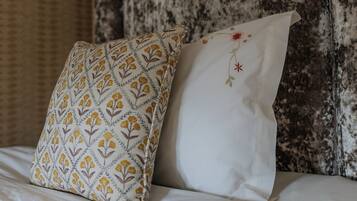 A bed with two pillows, one with a floral pattern and the other plain.