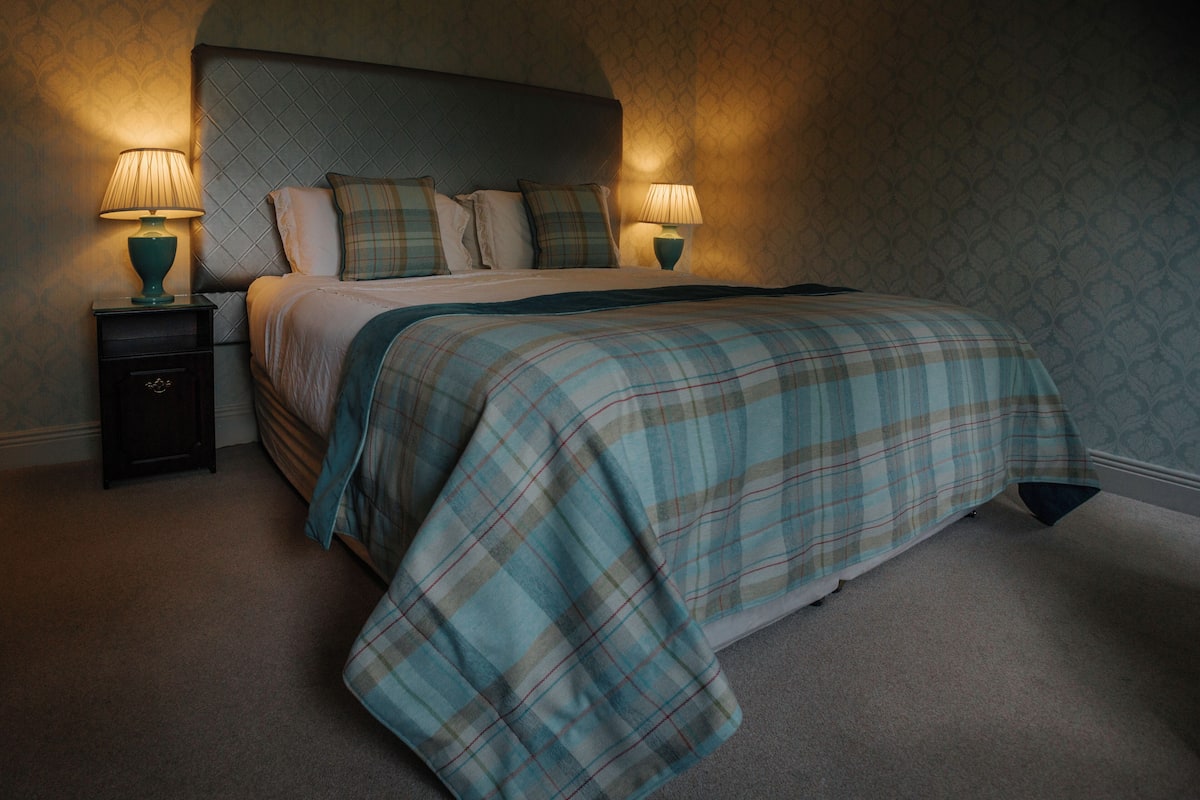 A bedroom with a bed, two bedside tables, and two lamps.
