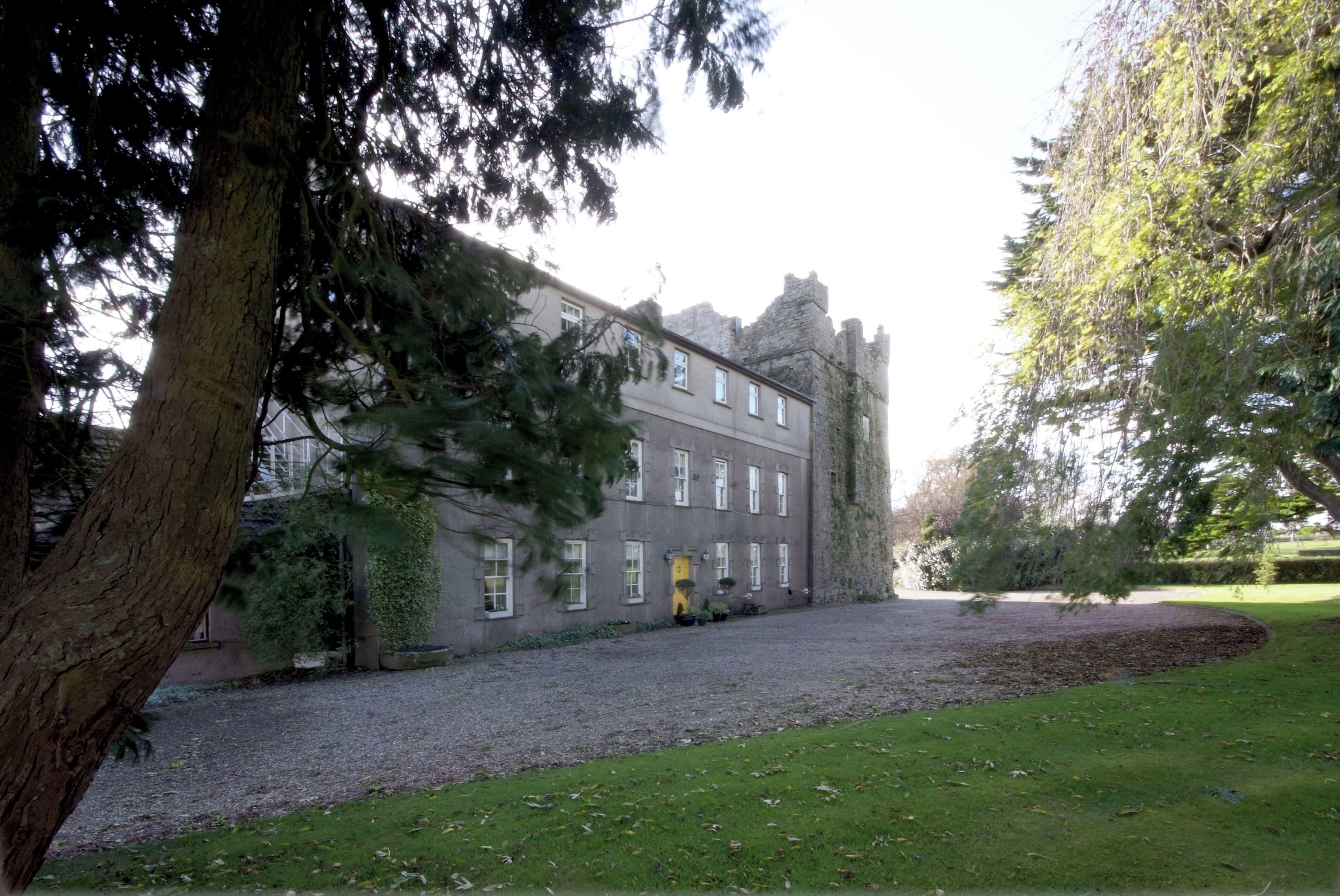 A large, historic building with a symmetrical facade, a central entrance, and a well-maintained lawn in front.