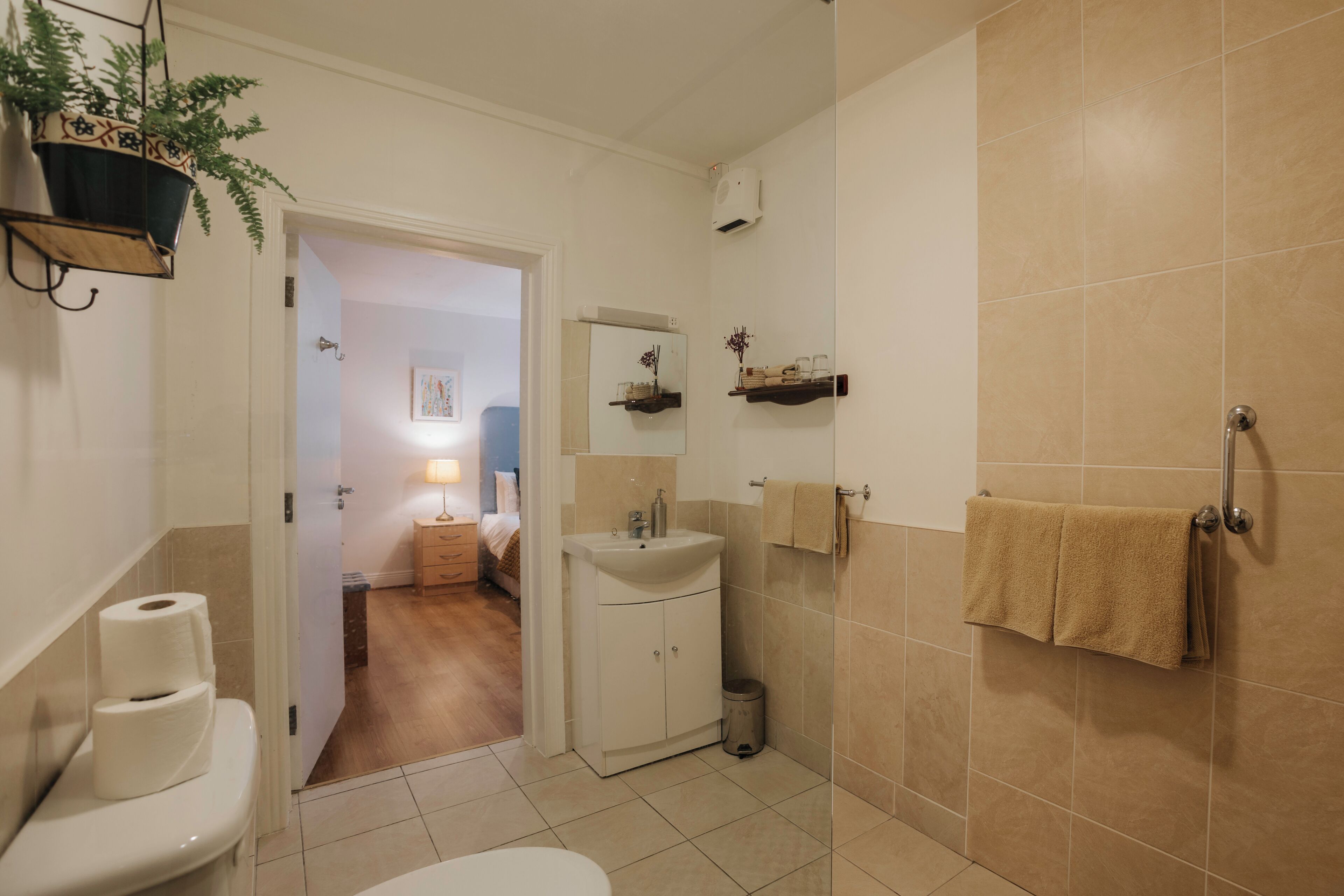 Un baño con inodoro, lavamanos y perchero para toallas.