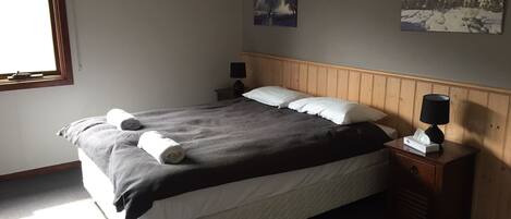 A neatly made bed with rolled towels, a bedside lamp, and a nightstand with a tissue box.