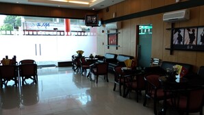 A spacious indoor seating area with tables and chairs, a television mounted on the wall, and an air conditioning unit. - Hotel Sogo Cabanatuan (Cabanatuan)