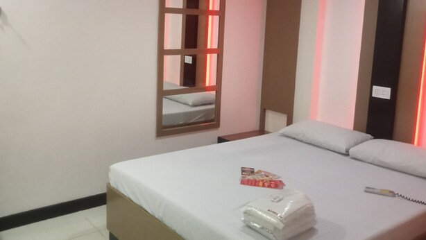 A hotel room with a bed, a bedside table, a mirror, and a red-lit wall. - Hotel Sogo Cabanatuan (Cabanatuan)