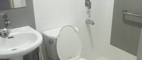 Casa de banho com sanita, lavatório e chuveiro.