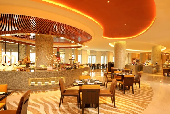 Un hall de hotel amplio con una barra central, diversas opciones de asientos y un diseño moderno con techo curvo y columnas iluminadas.