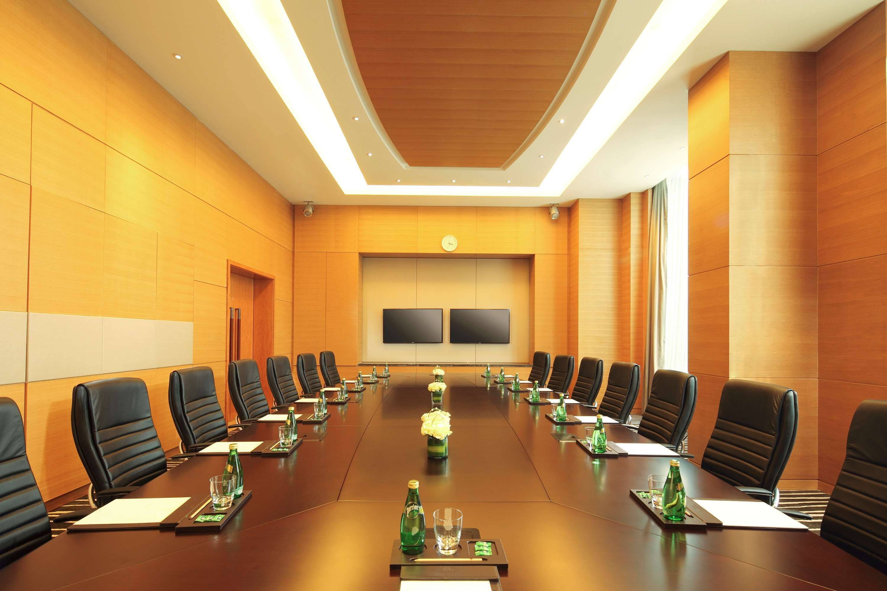 A conference room with a long table, black chairs, and a floral centerpiece.