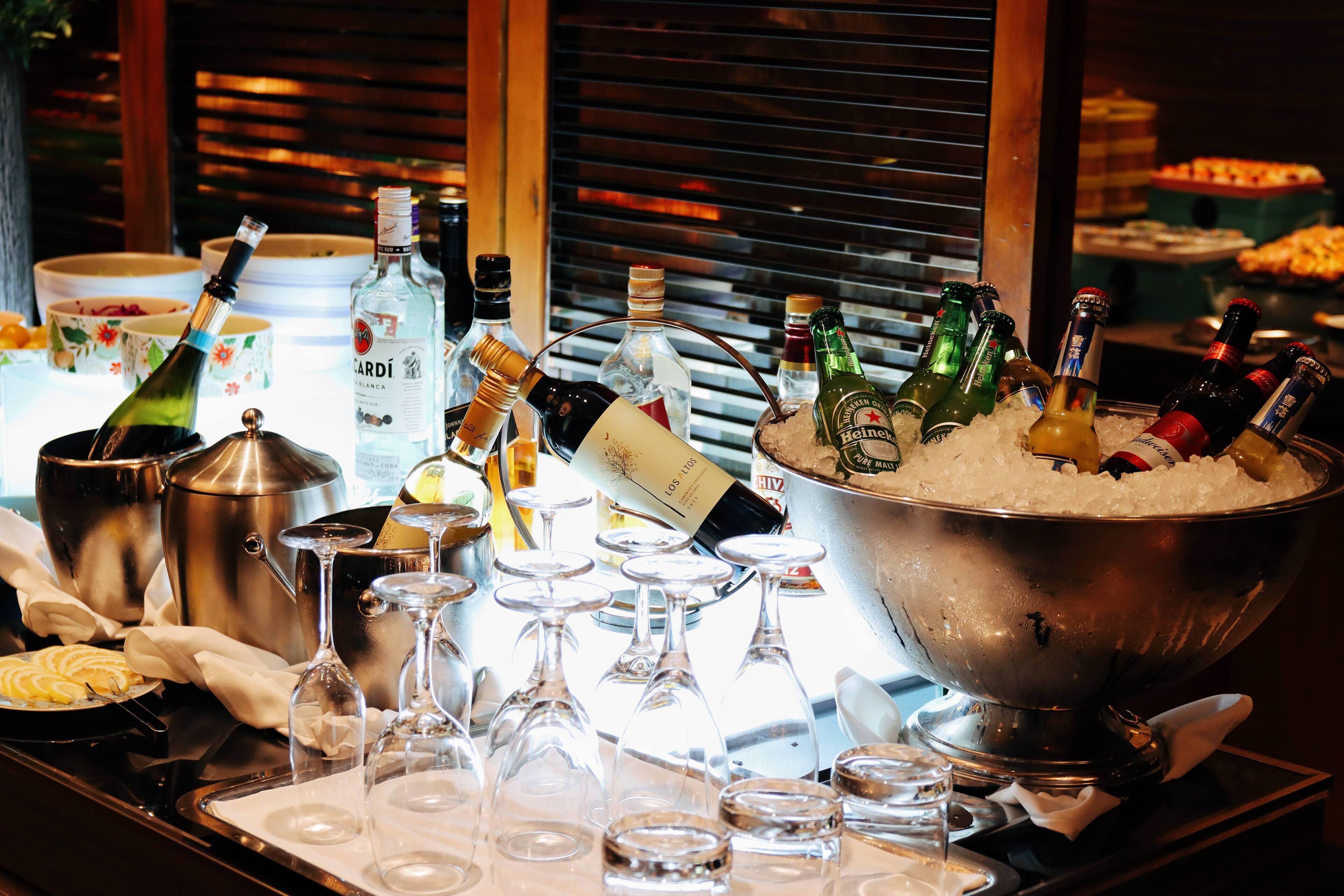 A bar area with bottles of alcohol, glasses, and a large bowl of ice.