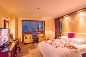 Una camera d'albergo con un letto, una scrivania, una TV e una finestra vista città.