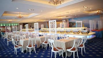 A hotel dining area with multiple tables and chairs, a central bar, and decorative light fixtures.