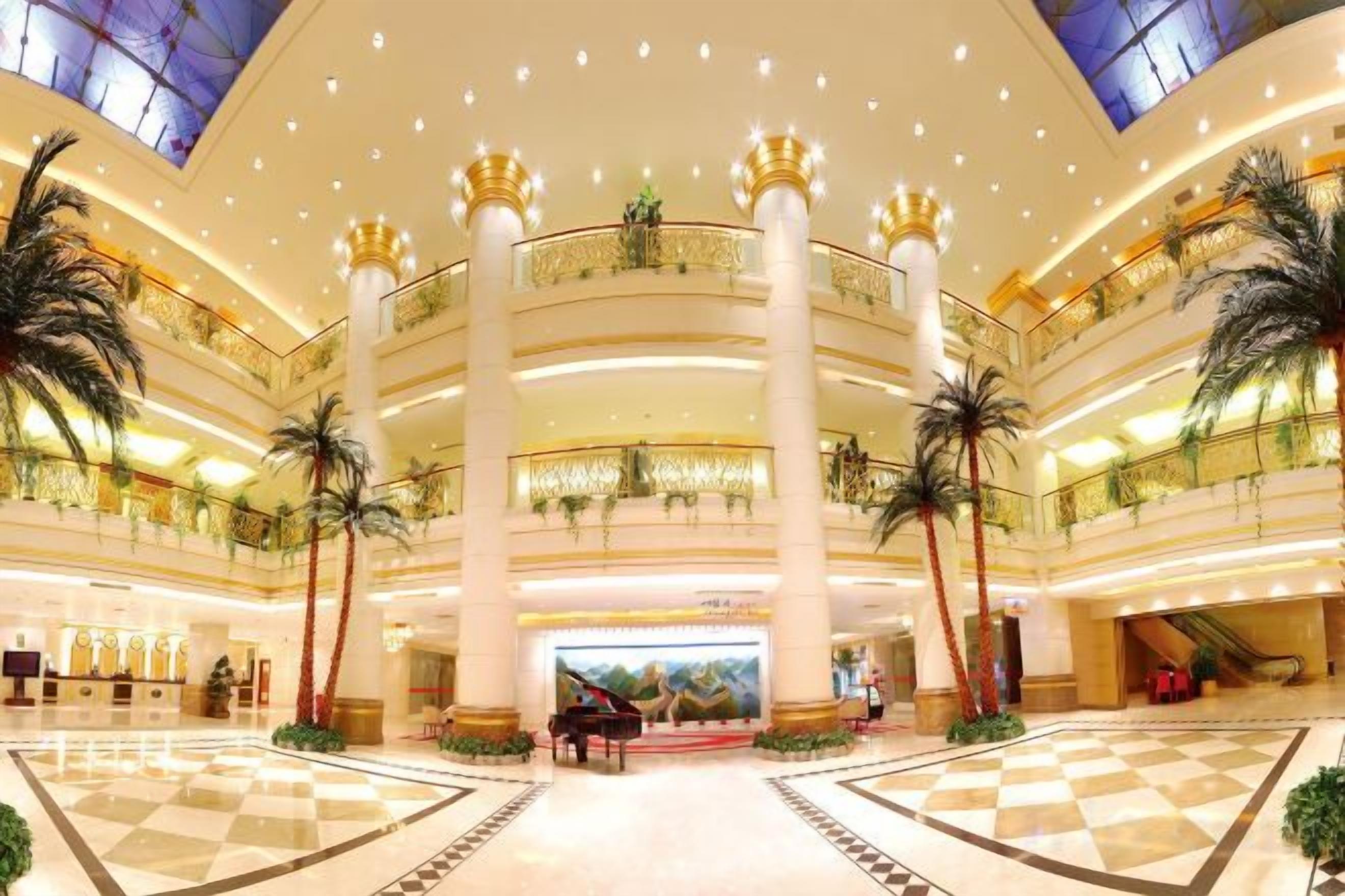 A multi-level atrium with a checkered floor, palm trees, and a central column.