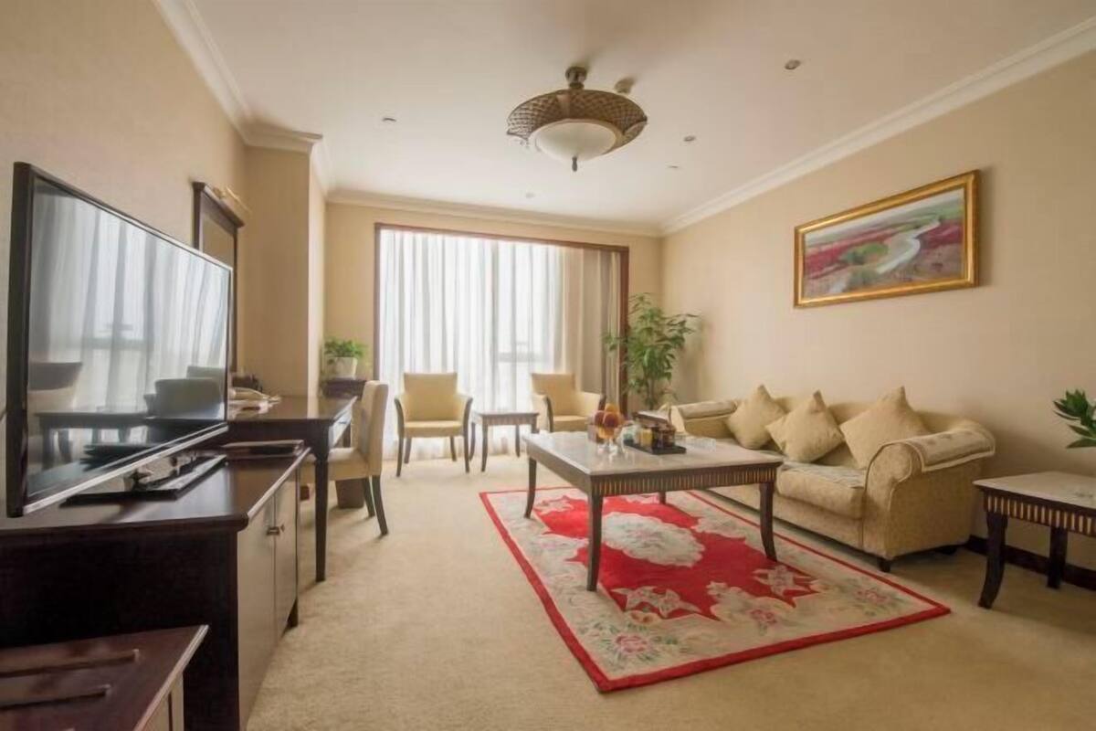 Uma sala de estar com televisão, sofá, mesa de centro e cadeiras.