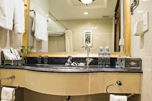 Un bagno con lavandino, specchio, portascopevoli e un quadro appeso al muro.